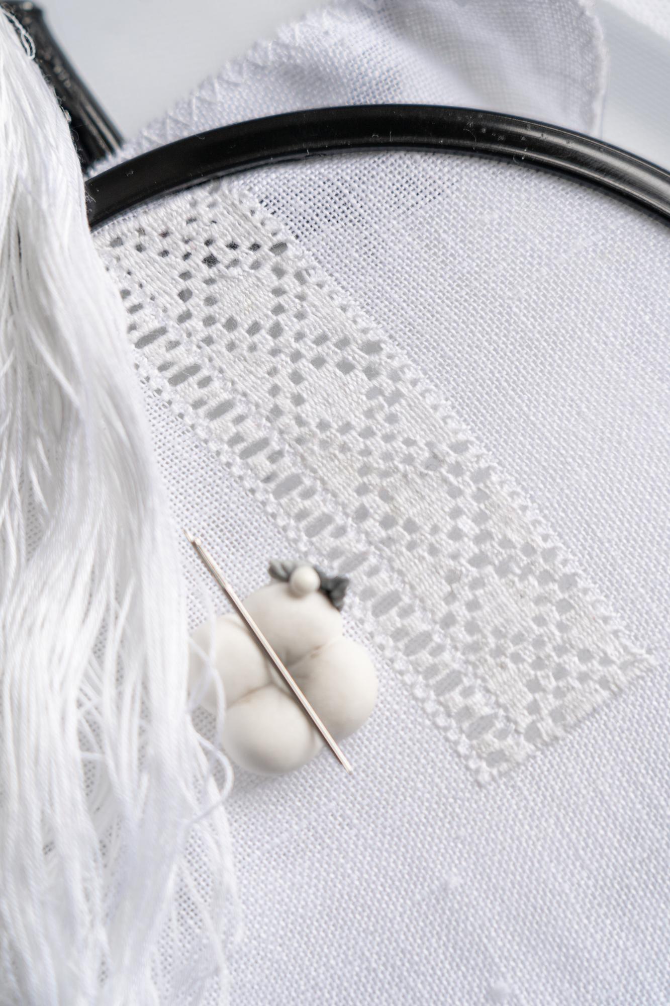 Artisan stitching a patterned textile in warm studio light